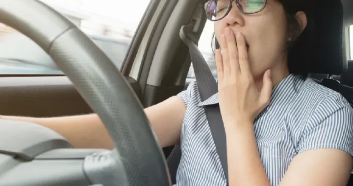 一名女性駕駛在汽車內因嚴重睡眠不足而張口打哈欠，眼神顯露疲態，展示了微睡眠入侵前常見的神經疲勞與生理崩潰訊號。