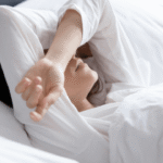 一名處於睡眠狀態的人在晨光中以手遮眼，視覺化呈現光照對晝夜節律中樞的干擾，隱喻現代人睡眠剝奪與生理時鐘混亂對代謝穩定性的影響。